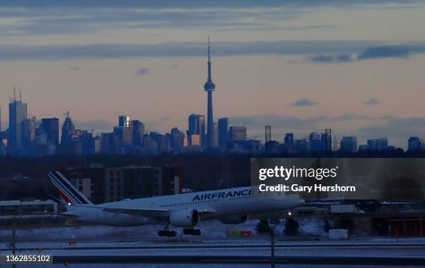 An Air France airplane lands in front of the CN Tower and skyline of downtown Toronto at Pearson International Airport on January 3 in Toronto,...