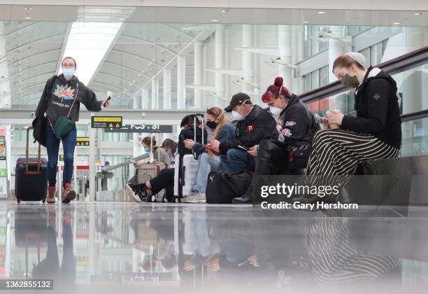 Woman runs through Terminal 1 as people use their mobile phones while they wait to board flights at Pearson International Airport on January 4 in...