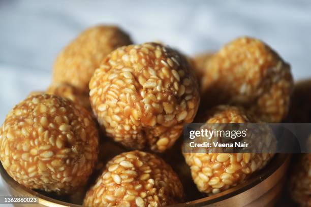 close-up of jaggery coated sesame/til laddu/laddoo in a brass utensil/urli/makar sankranti/india - makar sankranti stock pictures, royalty-free photos & images