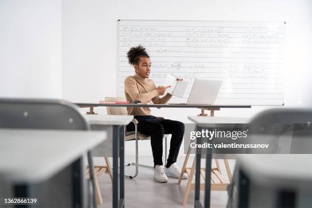 an african male teacher in an empty classroom teaches students online - virtual coach stock pictures, royalty-free photos & images