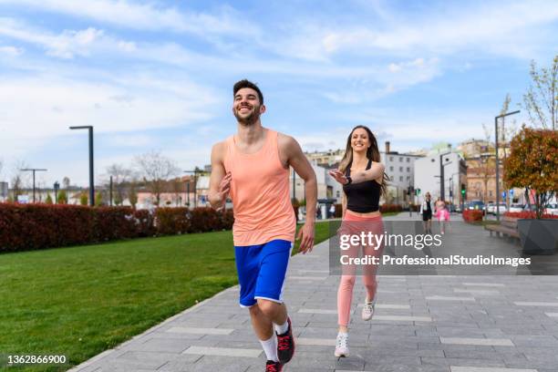 a beautiful young couple is running through the city. - rhythm stockfoto's en -beelden