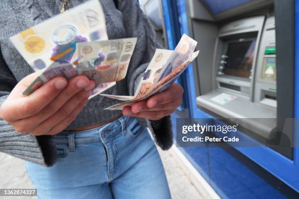 woman taking cash out of uk cash machine - budget uk stock pictures, royalty-free photos & images