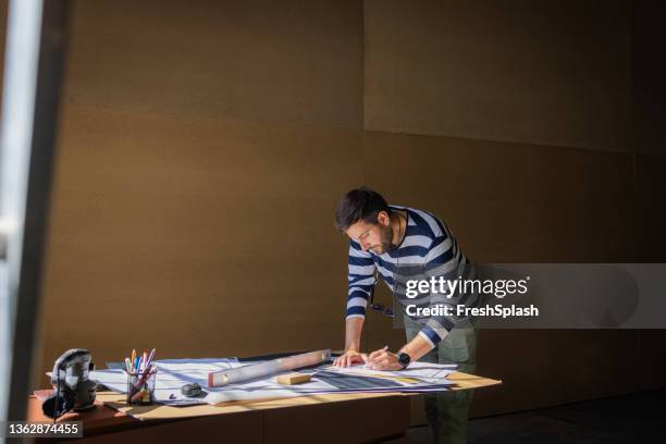 caucasian architect working on an architectural drawing of apartments in new building - architects stockfoto's en -beelden