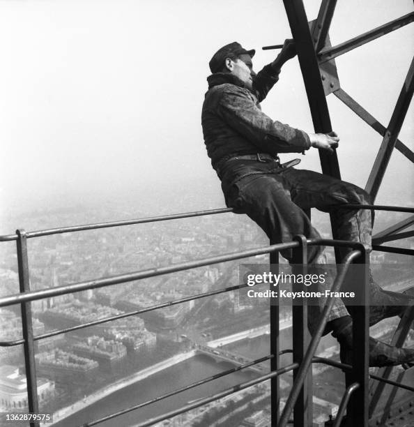 Un ouvrier effectue des travaux de peinture sur la Trou Eiffel , le 20 mars 1953.