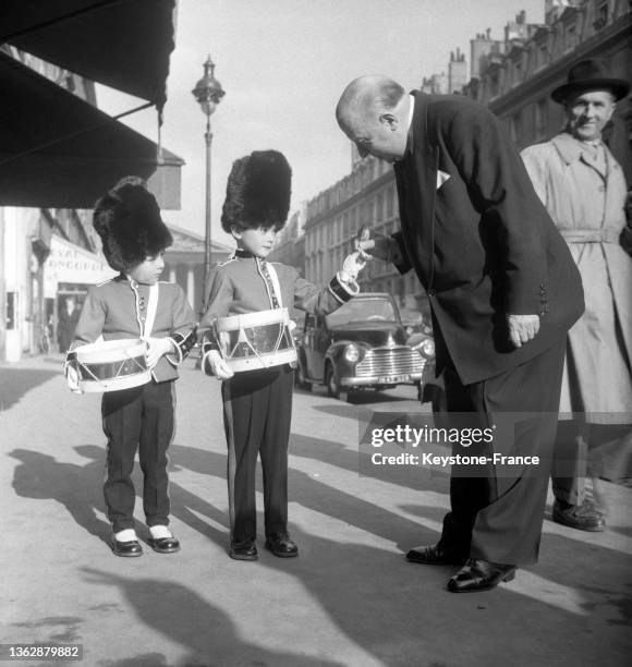 Monsieur Albert, Maître d'hôtel au "Maxim's" achète un coquelicot aux enfants costumés en tenue de grenadiers, le 12 novembre 1952.