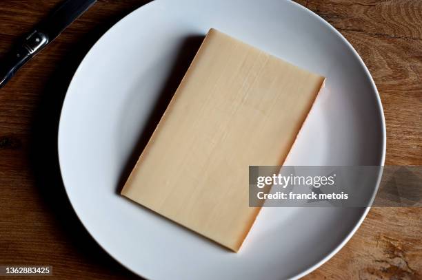 slice of comté cheese ( france) - comté stock pictures, royalty-free photos & images