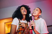 Best friends singing into a microphone on karaoke night