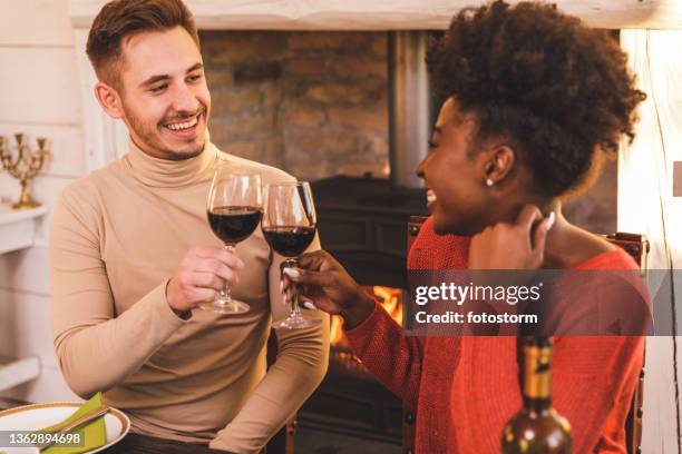 friend cheering to good health and happiness during dinner - winter dinner party stock pictures, royalty-free photos & images