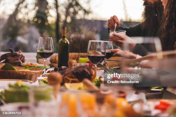 red wine, roast chicken and delicious sides being enjoyed during dinner - winter dinner party stock pictures, royalty-free photos & images