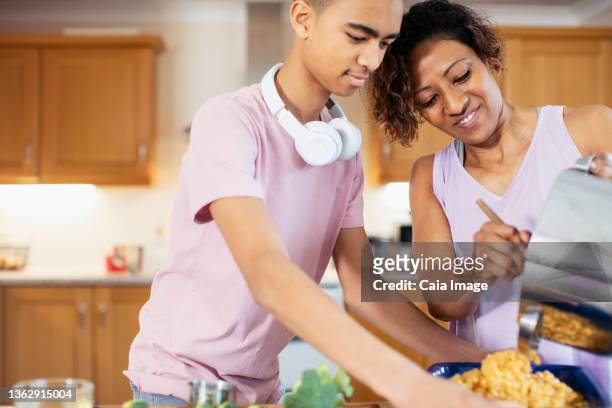 mother and teenage son cooking in kitchen - caiaimage stock-fotos und bilder