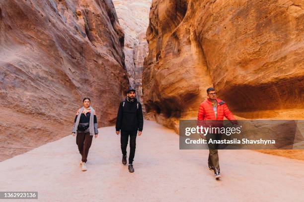 friends travelers exploring the ancient world of petra in jordan walking inside the canyon - middle east friends stock pictures, royalty-free photos & images