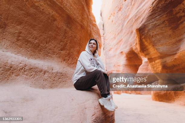 female traveler exploring the ancient world of petra in jordan walking inside the canyon - international landmark stock pictures, royalty-free photos & images