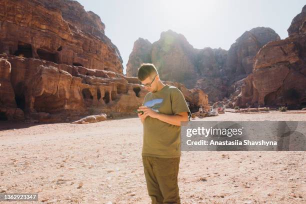 male traveler using smartphone at the petra in jordan during sunny day - geology class stock pictures, royalty-free photos & images