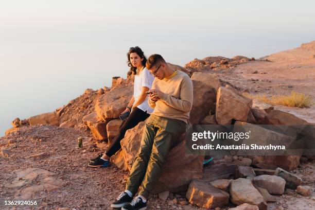 viajeros amigos contemplando la pintoresca puesta de sol sobre el mar muerto en jordania - fond orange fotografías e imágenes de stock