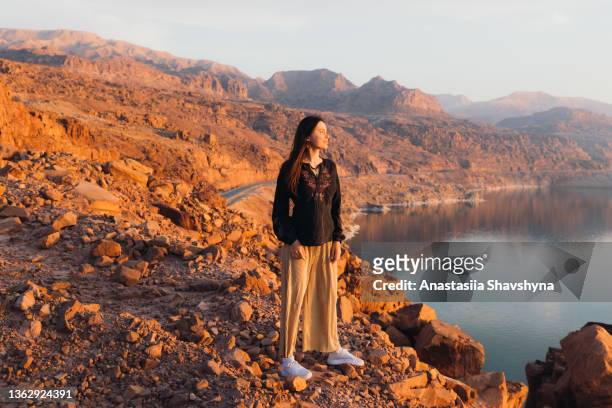 glückliche weibliche reisende, die den malerischen sonnenuntergang über dem toten meer und den bergen betrachtet - frau ruhige szene berge stock-fotos und bilder