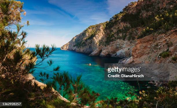view from a hiking trail of the picturesque rock formation and a beautiful turquoise blue bay near sa foradada - coastal feature stock pictures, royalty-free photos & images