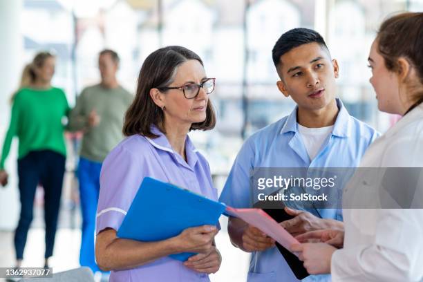nurses and doctors discussing a treatment plan - nhs england stock pictures, royalty-free photos & images