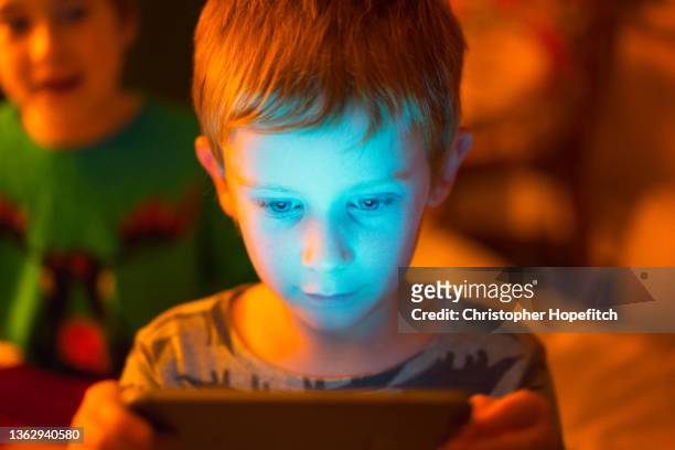 a young boy fascinated by what he is looking at on a tablet computer - ipad glow foto e immagini stock