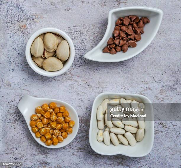 presentation of ingredients for wall charts in small white dishes of different shapes (haricot blanc, pépites de chocolats, pistache,…) - pépites stock pictures, royalty-free photos & images