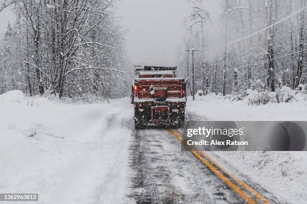 a snowplow clears snow from a road during a blizzard in british columbia - sneeuwschuiver stockfoto's en -beelden