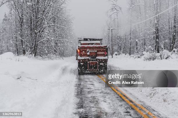 a snowplow clears snow from a road during a blizzard in british columbia - extreme weather stock pictures, royalty-free photos & images
