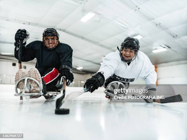 mature disabled latin woman and her partner practising sledge hockey - female hockey player stock pictures, royalty-free photos & images