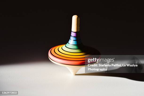 rainbow colored wooden spinning top on white surface - kreisel stock-fotos und bilder