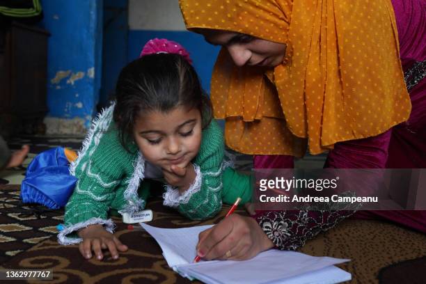 Aisha Mohammed Ali a mother of five who is a refugee from Aleppo, Syria, teaches the alphabet to one of her daughters, on January 5, 2022 in Tripoli,...