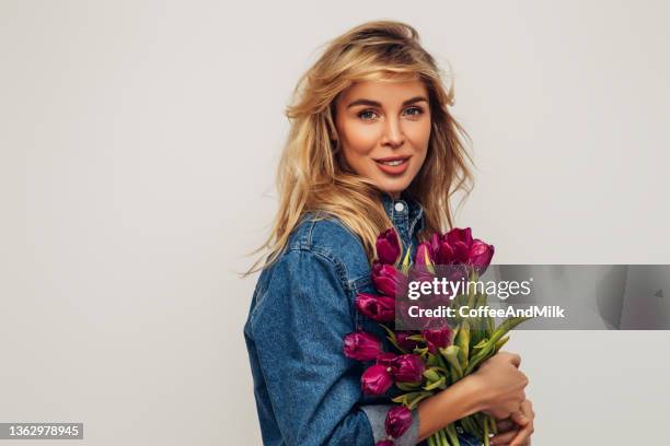 beautiful woman wearing jeans jacket and holding a bouquet of flowers - alleen één jonge vrouw stockfoto's en -beelden