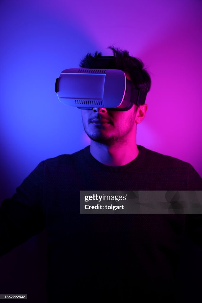 He is discovering metaverse by using VR glasses under neon lights