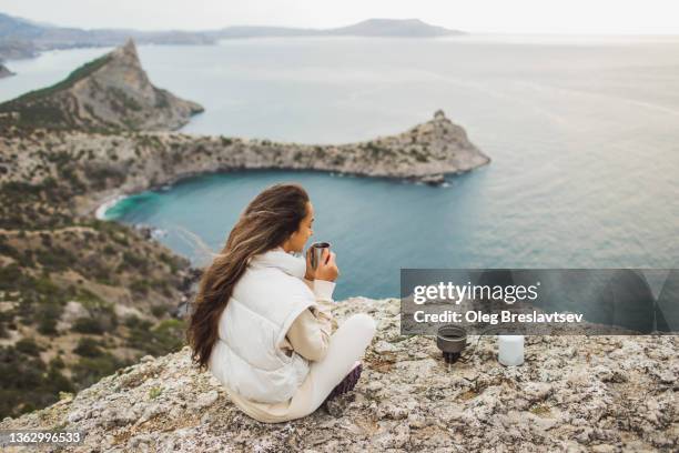 young tourist woman sitting on mountain top with amazing view and drinking morning coffee, made with gas stove - türkei tee stock-fotos und bilder