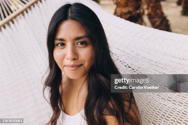 portrait of a latina young woman looking at camera with a little smile on her face - office smile light stock-fotos und bilder