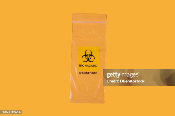 plastic specimen bag with the biohazard logo on a yellow background. waste, pollution, covid-19, virus, omicron, delta and ihu concept. - medical sample stock pictures, royalty-free photos & images