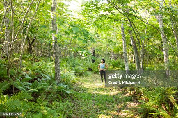 young female jogger standing in the forest - forward athlete foto e immagini stock