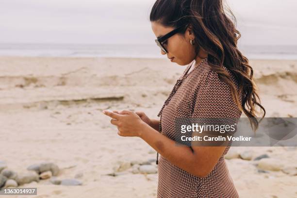 side view of long hair  latina woman working from the beach - beach goers stock pictures, royalty-free photos & images