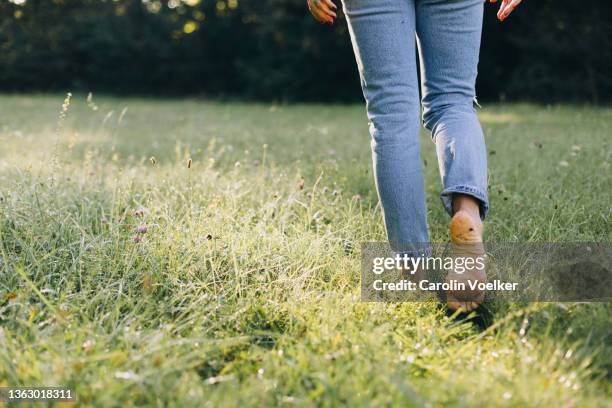 low angle view of a person walking barefooted on the grass - barefoot foto e immagini stock