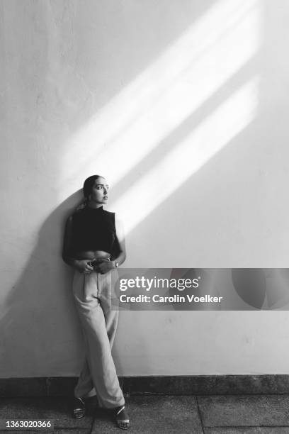 full length portrait on black and white of a brazilian woman standing against a wall looking up - woman standing full length stock pictures, royalty-free photos & images