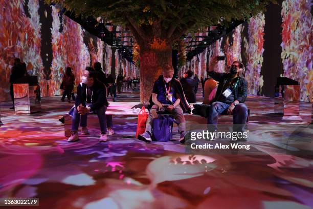 Attendees watch a 360-degree video presentation at the South Korea-based SK Group booth at CES 2022 at the Las Vegas Convention Center on January 5,...