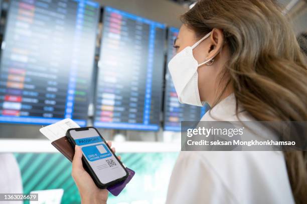 traveler holds vaccine passport certificate to show covid 19 vaccination status - compulsory photos et images de collection