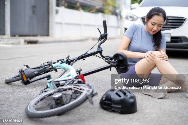 cyclist woman having knee pain after impact the floor by accident car crash on the road. - joint body part stock pictures, royalty-free photos & images