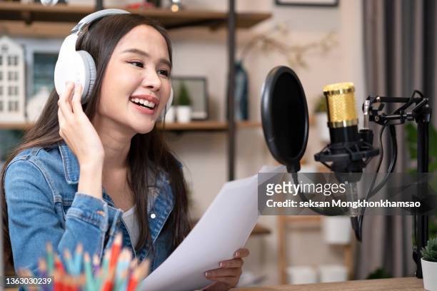 woman blogger with long black hair recording online podcast using her laptop, headphones and professional microphone in a studio. - animateur radio photos et images de collection