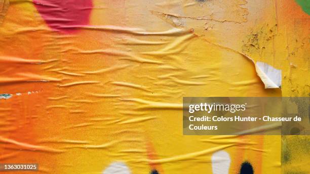 yellow and orange paper stuck and torn on a wall in paris - collant description physique photos et images de collection