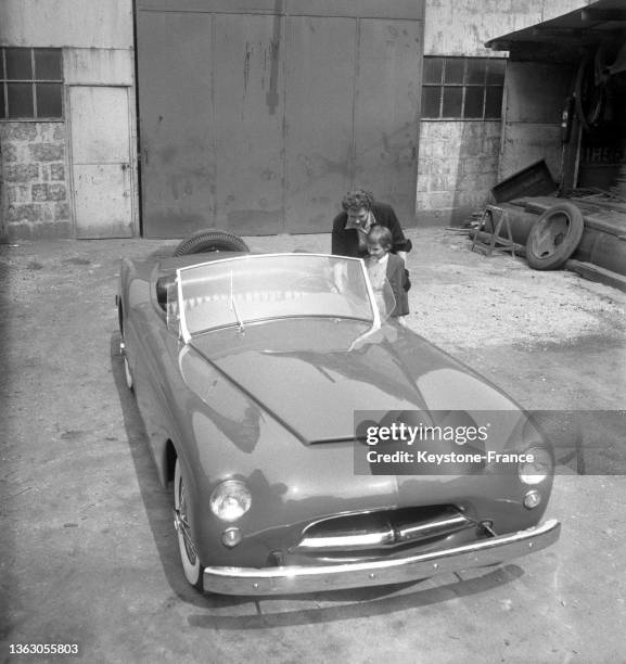Une mère et son enfant observent les nouveaux matériaux plastique des carrosseries de voiture présentées au du Salon de la Chimie , le 11 juin 1953.