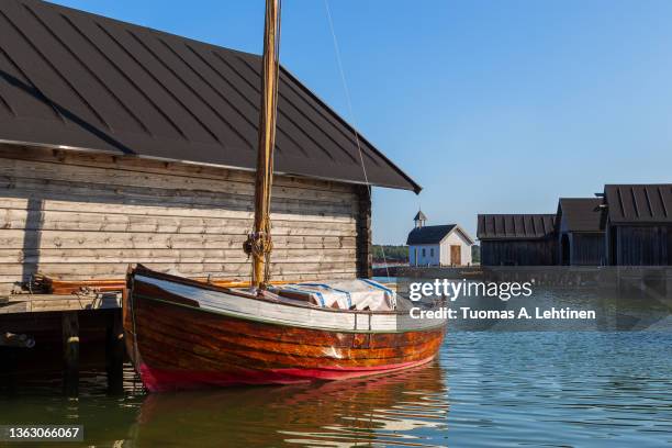 old traditional wooden boathouses, an old sailing boat and seafarer's chapel at the maritime quarter in mariehamn, åland islands, finland, on a sunny day in the summer. - rimessa per barche foto e immagini stock