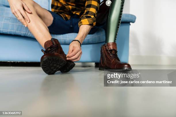 man with leg prosthesis tying his shoes - leg show fotografías e imágenes de stock