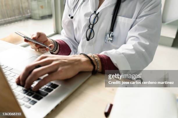 close-up of a female doctor using computer and smartphone - care fotografías e imágenes de stock