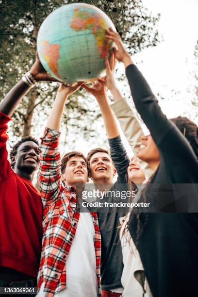 multiracial friends with globe at the park - international student stockfoto's en -beelden