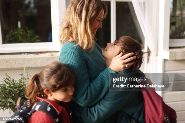 2 children hugging their mom before to go to school - enfant cartable photos et images de collection