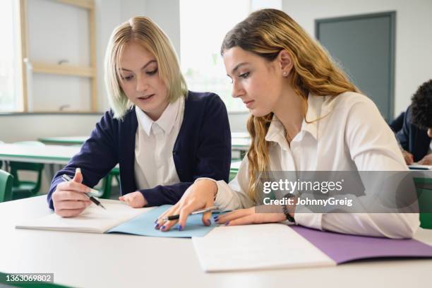 teenage schoolgirls discussing writing assignment in class - doing a favor stockfoto's en -beelden