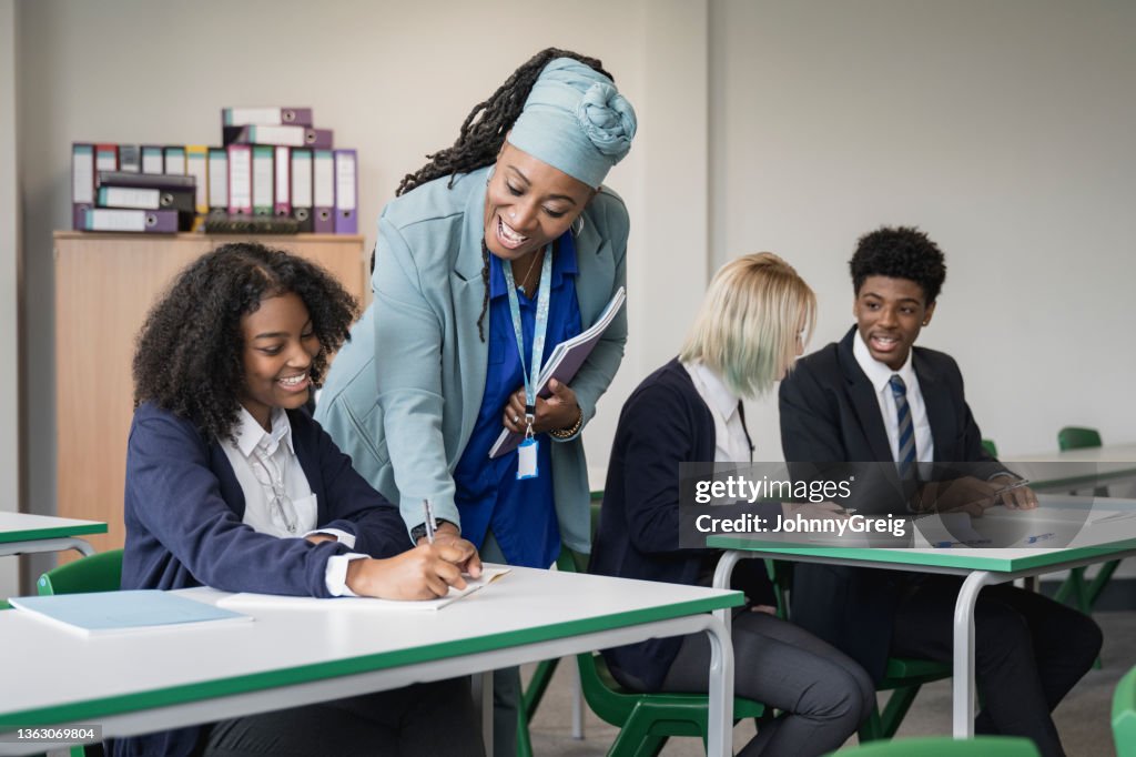 Fröhlicher Lehrer hilft Schüler im Sekundarunterricht